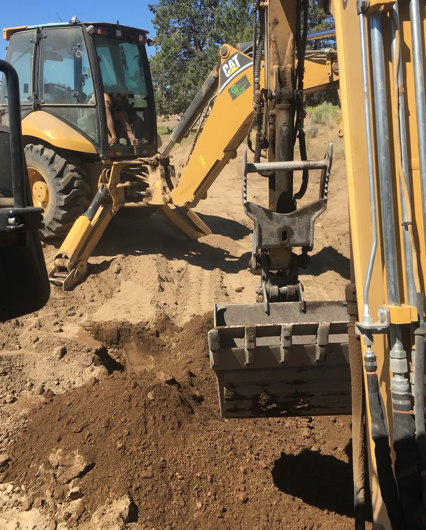 CAT backhoe excavating an active trench