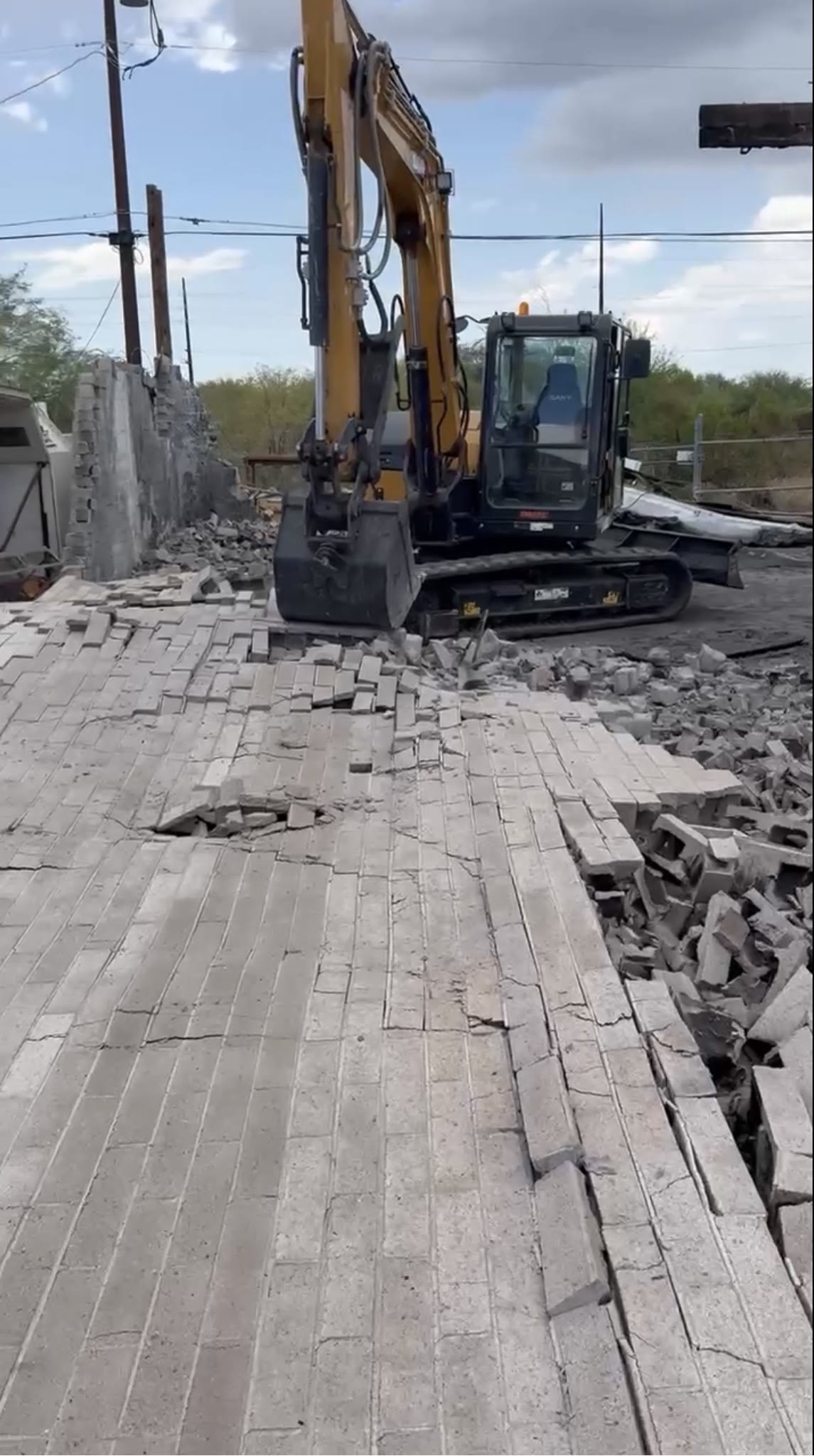 SANY excavator breaking up a block wall and concrete rubble