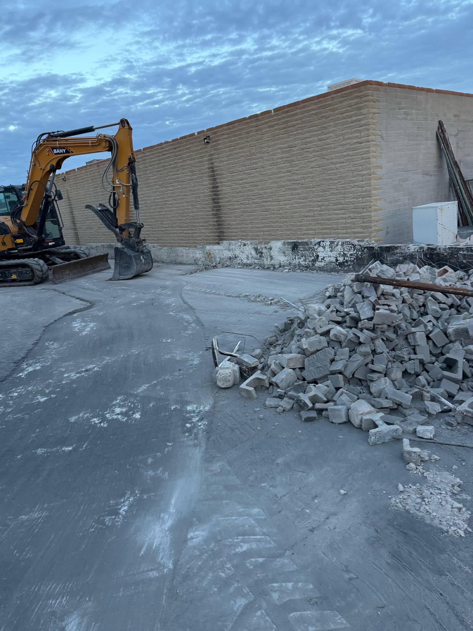 Excavator beside concrete rubble after site clearing