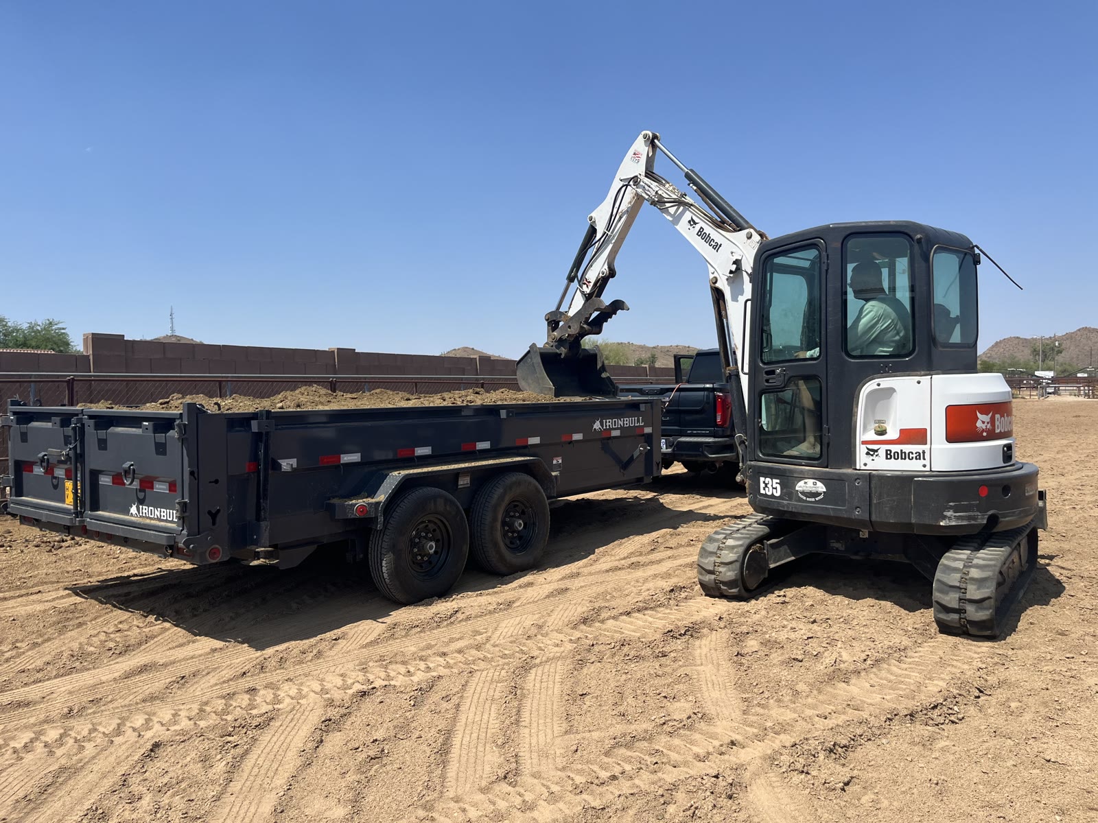 Bobcat excavator loading soil into a dump trailer