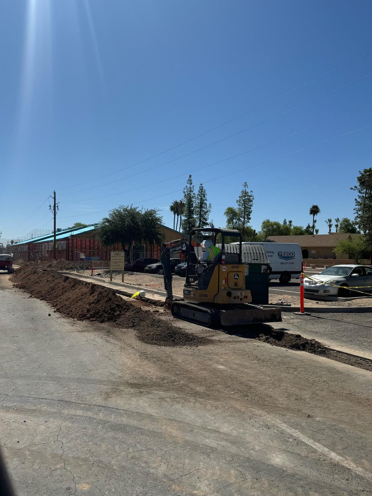 Deere excavator beside a clear roadside utility trench