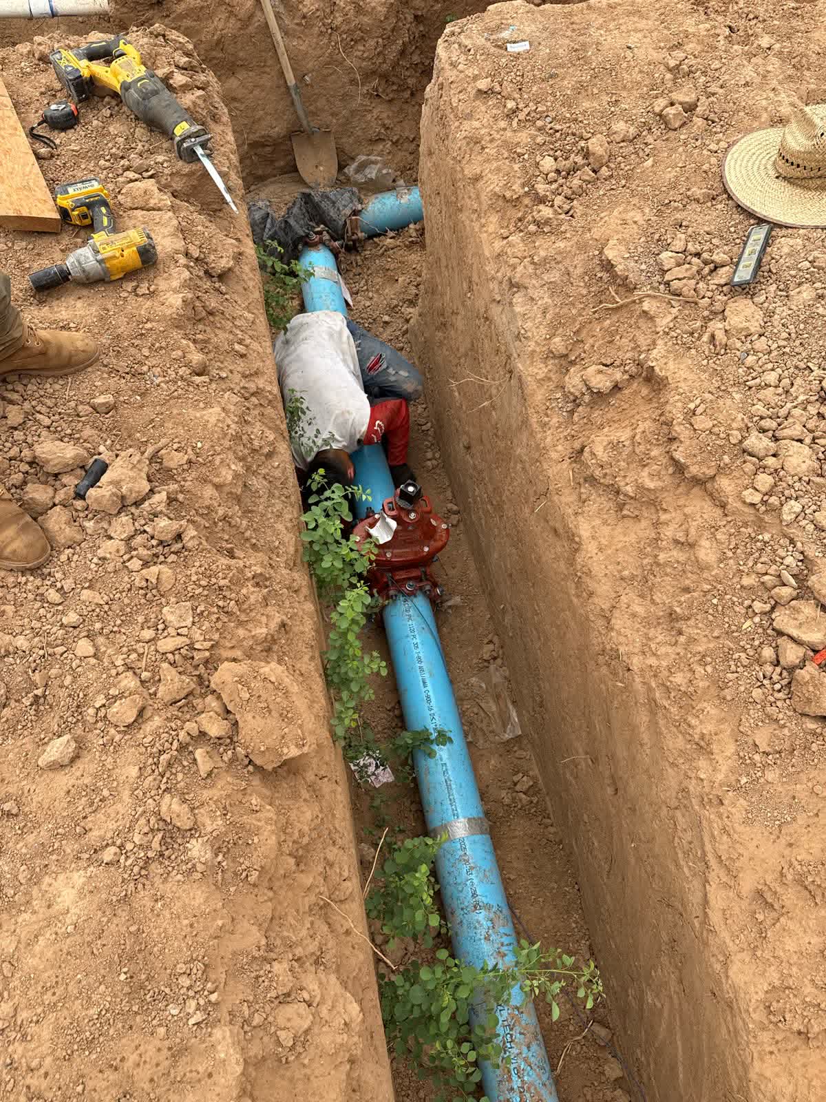 Blue water pipe with red valve in a utility trench